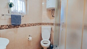 A bathroom with a toilet, a sink, a shower, and a window with curtains. - One Bedroom Apartment with Bacony and Sea View (Vrboska)