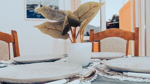 A dining table with a white vase containing large leaves, surrounded by wooden chairs. - One Bedroom Apartment with Bacony and Sea View (Vrboska)