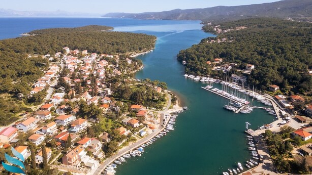 An aerial view of a coastal town with a marina, residential buildings, and a forested hillside. - One Bedroom Apartment with Bacony and Sea View (Vrboska)