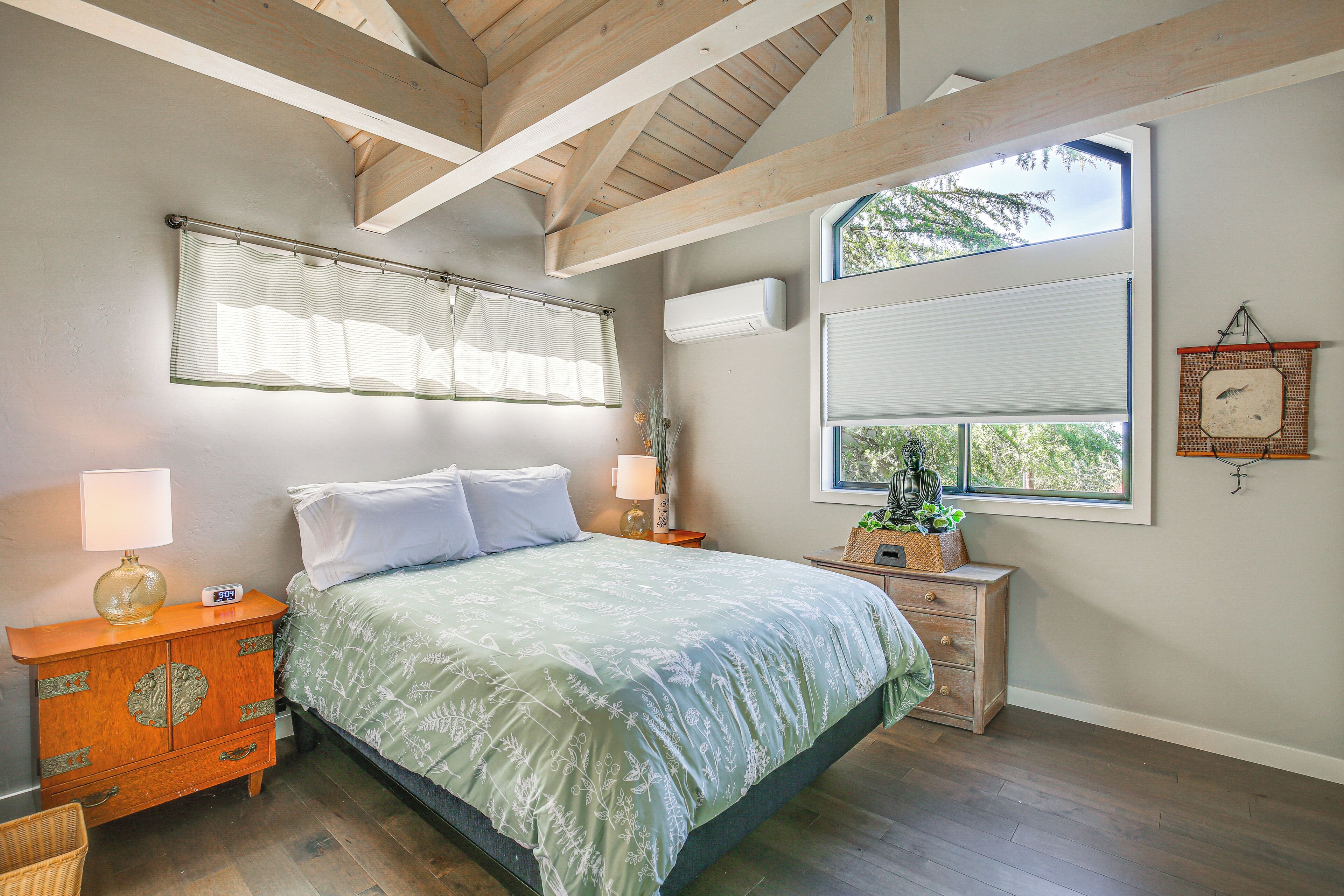 A bedroom with a bed, a nightstand, a dresser, and a window with blinds.
