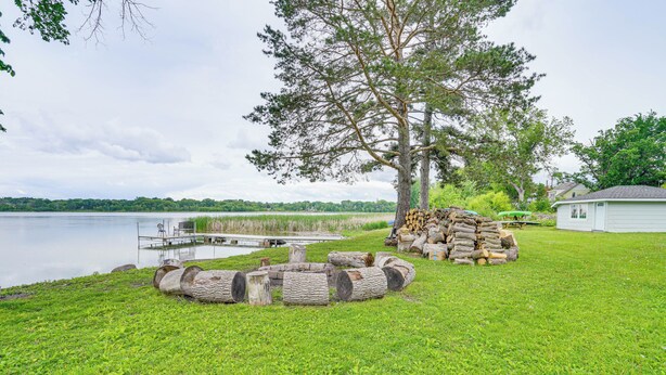 Una propiedad frente al lago con jardín, una fogata, un muelle y una casa.