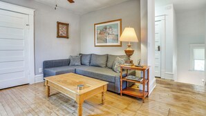 Una sala de estar con una mesa de centro de madera, un sofá gris, una mesita de noche con lámpara y un ventilador de techo.