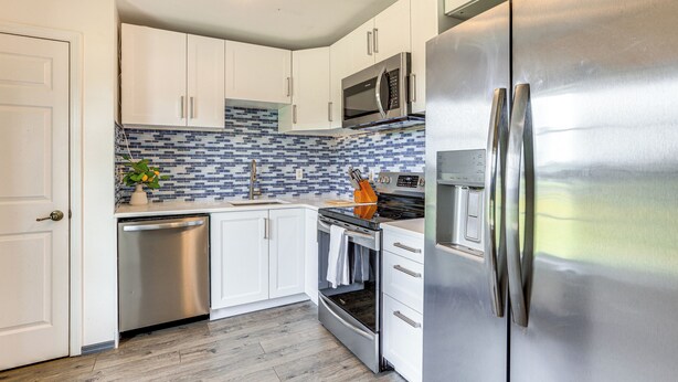 A modern kitchen with white cabinets, a stainless steel refrigerator, a microwave, and a dishwasher. - Idyllic Anthony Home: Riding Arena w/ Mirror Wall! (Anthony)