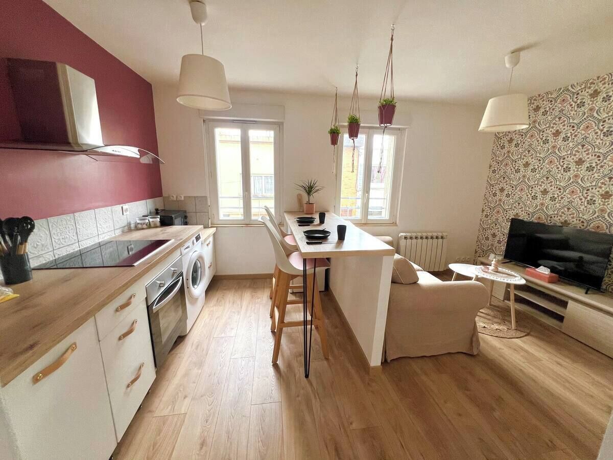 A modern kitchen with a central island, a dining area, and a living space with a TV.