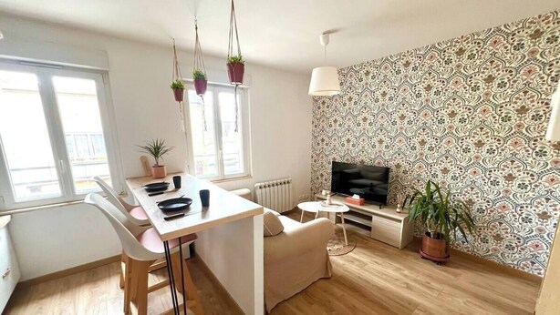 Un salon moderne comprenant un coin repas, un canapé, un téléviseur et des plantes en pot.
