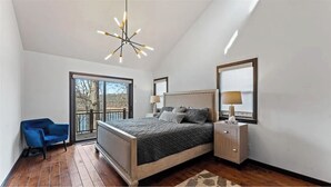 Ein Schlafzimmer mit einem großen Bett, einem Nachttisch, einem Sessel und Blick ins Freie.