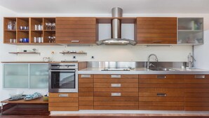 A modern kitchen with wooden cabinets, stainless steel appliances, and a built-in oven. - 6BD Villa for 12 with Heated Pool, Jacuzzi, First Row to the Sea (Punat)