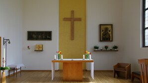 Interior de una iglesia con altar de madera, bancas y arte religioso.