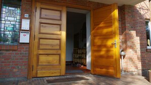 Una puerta de madera con un panel de vidrio, un muro de ladrillo y un buzón de metal.