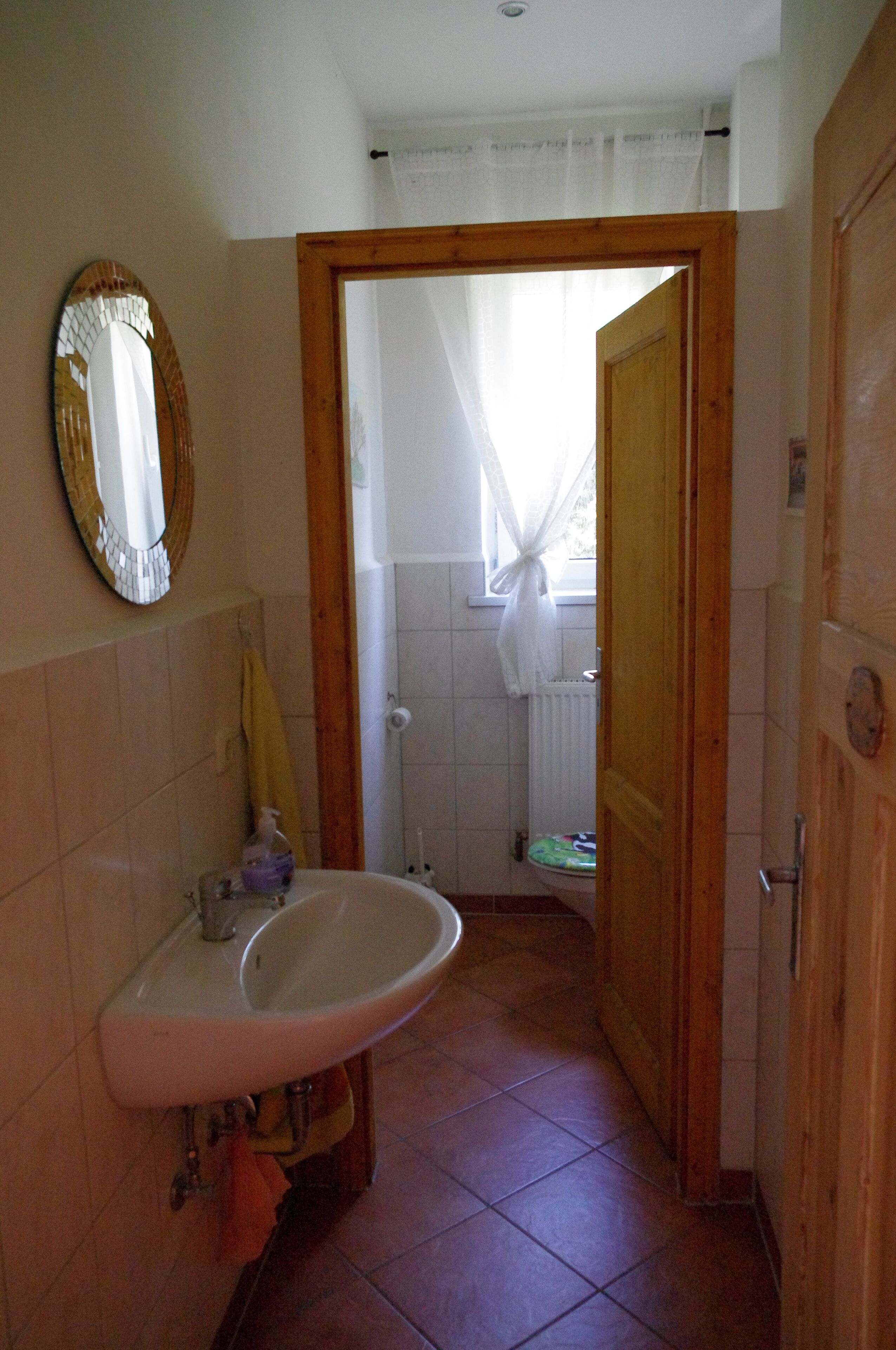 A bathroom with a sink, mirror, and wooden door.