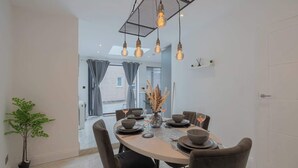 A dining area with a round table, chairs, and hanging light fixtures.