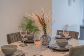 A dining table set with plates, bowls, and glasses, and a vase with dried plants.
