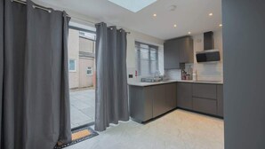 A modern kitchen with grey cabinets, a built-in microwave, and a window with blinds.
