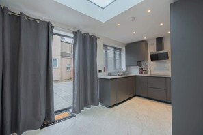 A modern kitchen with grey cabinets, a built-in microwave, and a window with blinds.