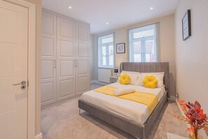A bedroom with a bed, a wardrobe, a nightstand, and a window.