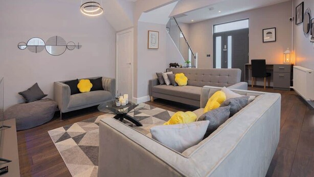 A modern living room with a sofa, a coffee table, and a staircase leading to another room.