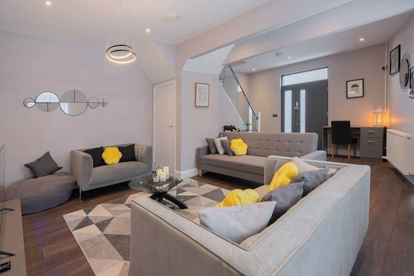 A modern living room with a sofa, a coffee table, and a staircase leading to another room.