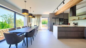A modern kitchen with a central island, built-in appliances, and a large window overlooking greenery.
