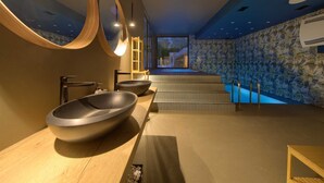 A modern bathroom with a large bathtub, two large bowls, and a wooden vanity.