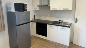 Cocina compacta equipada con refrigerador, microondas, horno, lavavajillas y pileta.