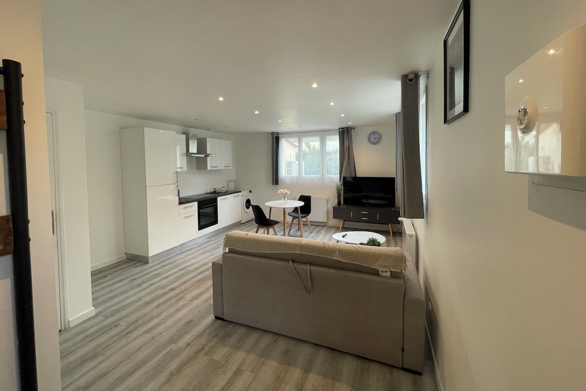 Um apartamento moderno com cozinha compacta, área de jantar e sala de estar.