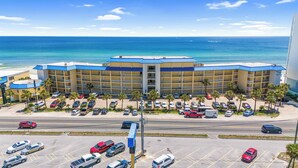 A multi-story hotel with a blue roof, located near a beach with clear blue waters. - Continental by Book That Condo (Panama City Beach)