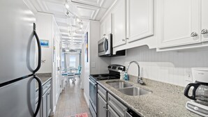 A modern kitchen with white cabinetry, stainless steel appliances, and a granite countertop. - Continental by Book That Condo (Panama City Beach)