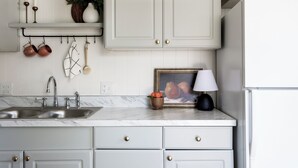 A kitchen with white cabinets, a marble countertop, a sink, and a refrigerator. - Charming Cottage on the Boise Bench. Minutes from downtown, BSU & the airport. (Boise)