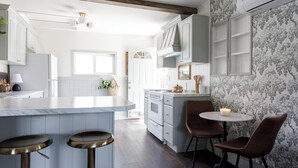 A kitchen with a marble countertop, wooden stools, and a round table with a candle. - Charming Cottage on the Boise Bench. Minutes from downtown, BSU & the airport. (Boise)