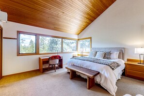 Relax in a spacious room with a high ceiling, large windows, and a neatly made bed.