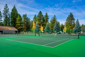 Play a game of tennis surrounded by lush trees and a picturesque clubhouse.