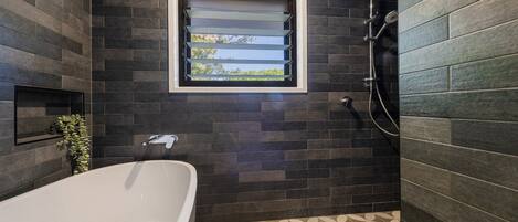 A modern bathroom with a bathtub, a window with a view, and a shower area.