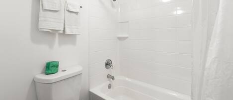 Un baño con inodoro, bañera y cortina de ducha.
