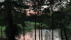 A serene lakeside scene with a chair and rocks near the water's edge, surrounded by dense trees. - RV Site #42 pull through - Big Rig Friendly 65ftx28ft (Hardin)