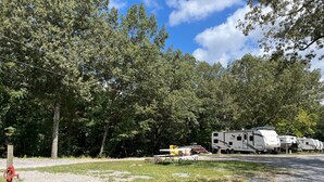 A campground with RVs, a gravel path, and trees. - RV Site #38 Pull Through (Hardin)