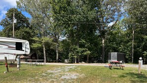 A campsite with a trailer, picnic table, and utility box. - RV Site #39 Pull Through (Hardin)