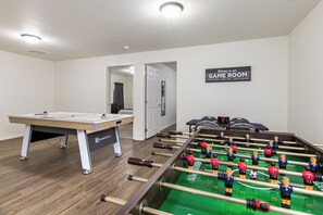 Une salle de jeux équipée d’un baby-foot, d’une table de billard et d’une pancarte sur laquelle on peut lire : « Bienvenue dans notre salle de jeux ».