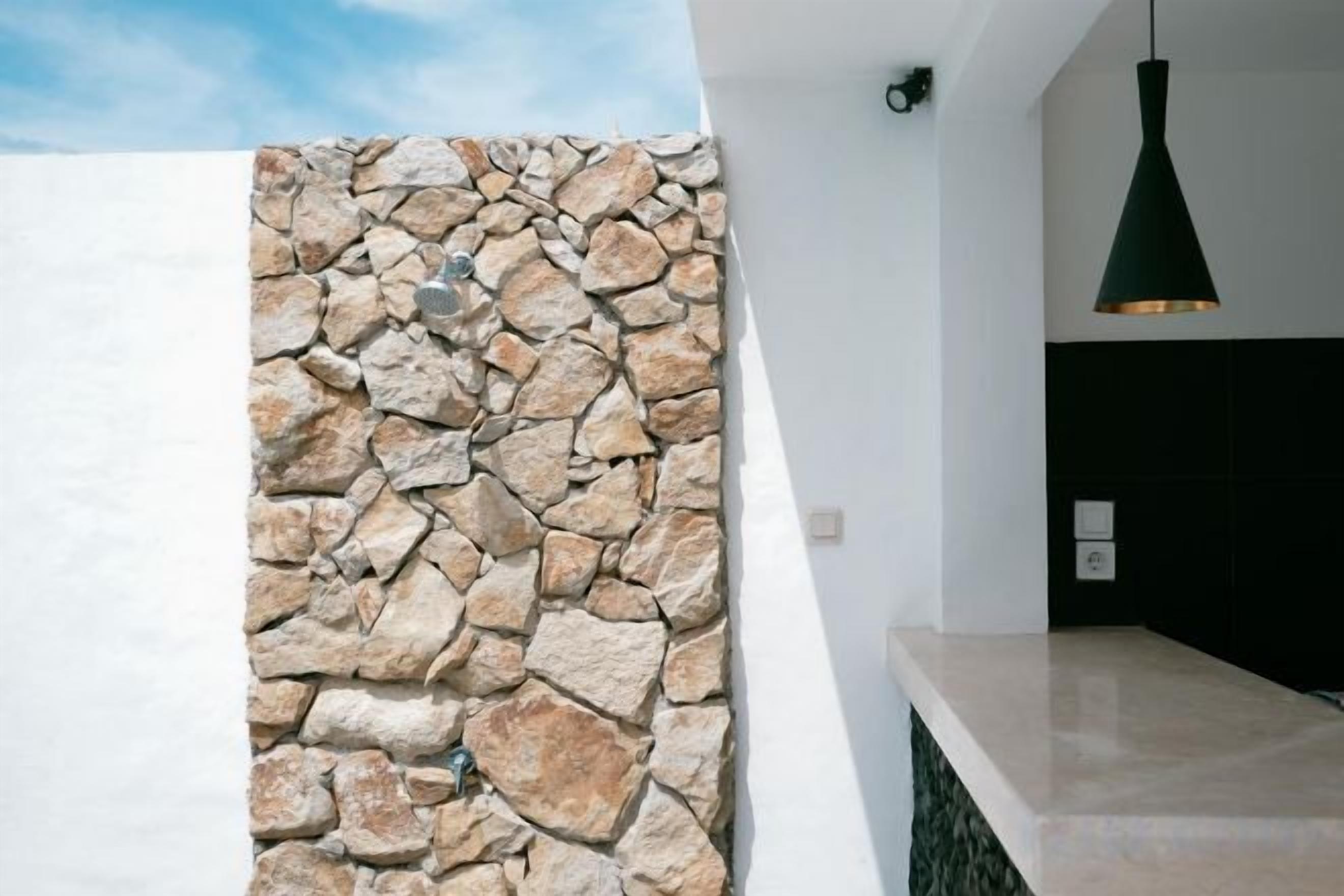 Un interior modern amb una paret de pedra, una paret blanca i un panell negre.