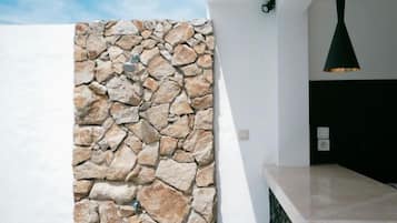 Un interior modern amb una paret de pedra, una paret blanca i un panell negre.