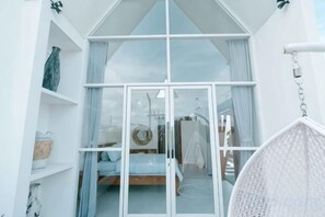 A bedroom with a bed, a wardrobe, a hanging chair, and a large window.