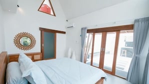 A bedroom with a bed, a wooden headboard, a large window with curtains, and a wall-mounted decorative item. - The Lavana Hidden Villa Lombok (Mataram)