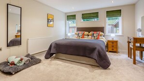 Une chambre à coucher avec un grand lit, une table de chevet, une chaise, un miroir et un radiateur.