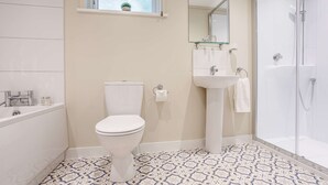 Une salle de bain comprenant des toilettes, un lavabo, une baignoire et une douche.