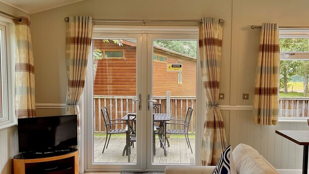 A living room with a TV, sofa, and a dining table. - Holiday Lodge in The Cotswolds (Kingham)