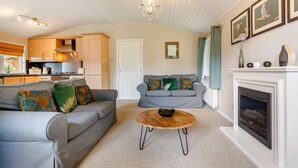 A living room with a grey sofa, a round coffee table, and a fireplace. - Holiday Lodge in The Cotswolds (Kingham)