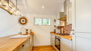 A modern kitchen with wooden countertops, a built-in oven, and white cabinetry. - Holiday Lodge in The Cotswolds (Kingham)