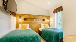 A room with two beds, each with a green bedspread, wooden headboard, and bedside lamps. - Holiday Lodge in The Cotswolds (Kingham)