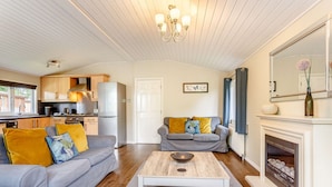 A modern living room with a grey sofa, a coffee table, and a fireplace. - Holiday Lodge in The Cotswolds (Kingham)