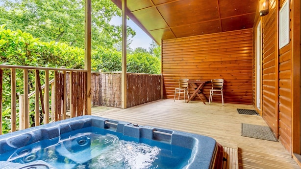 Eine Holzterrasse mit Whirlpool, Holzwänden und einem Tisch mit Stühlen.