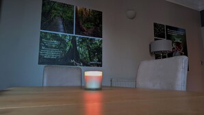 A room with a wooden table, a lit candle, and posters on the wall.